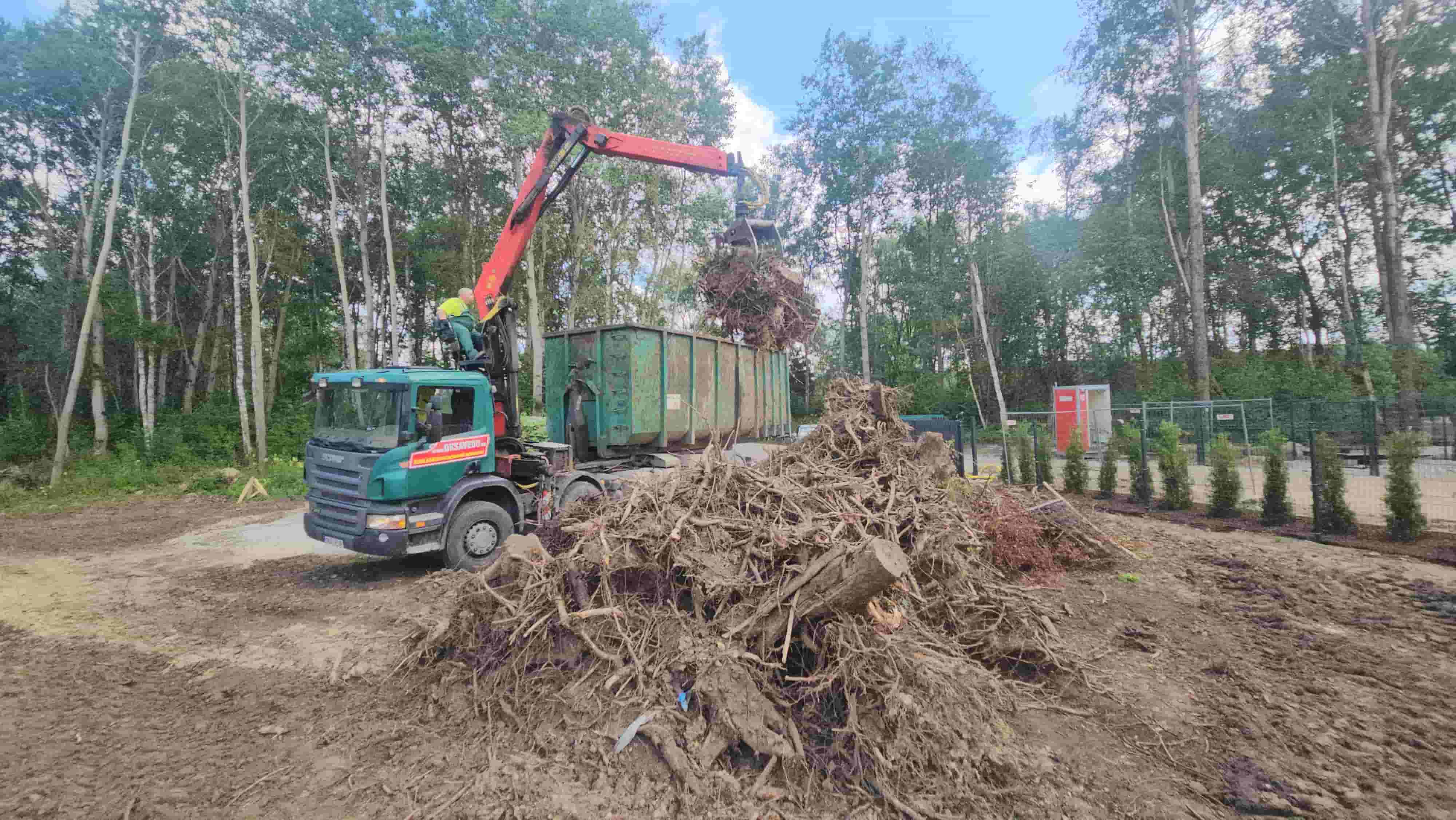 Greiferiga kraanaauto laadib kändusid konteinerisse.