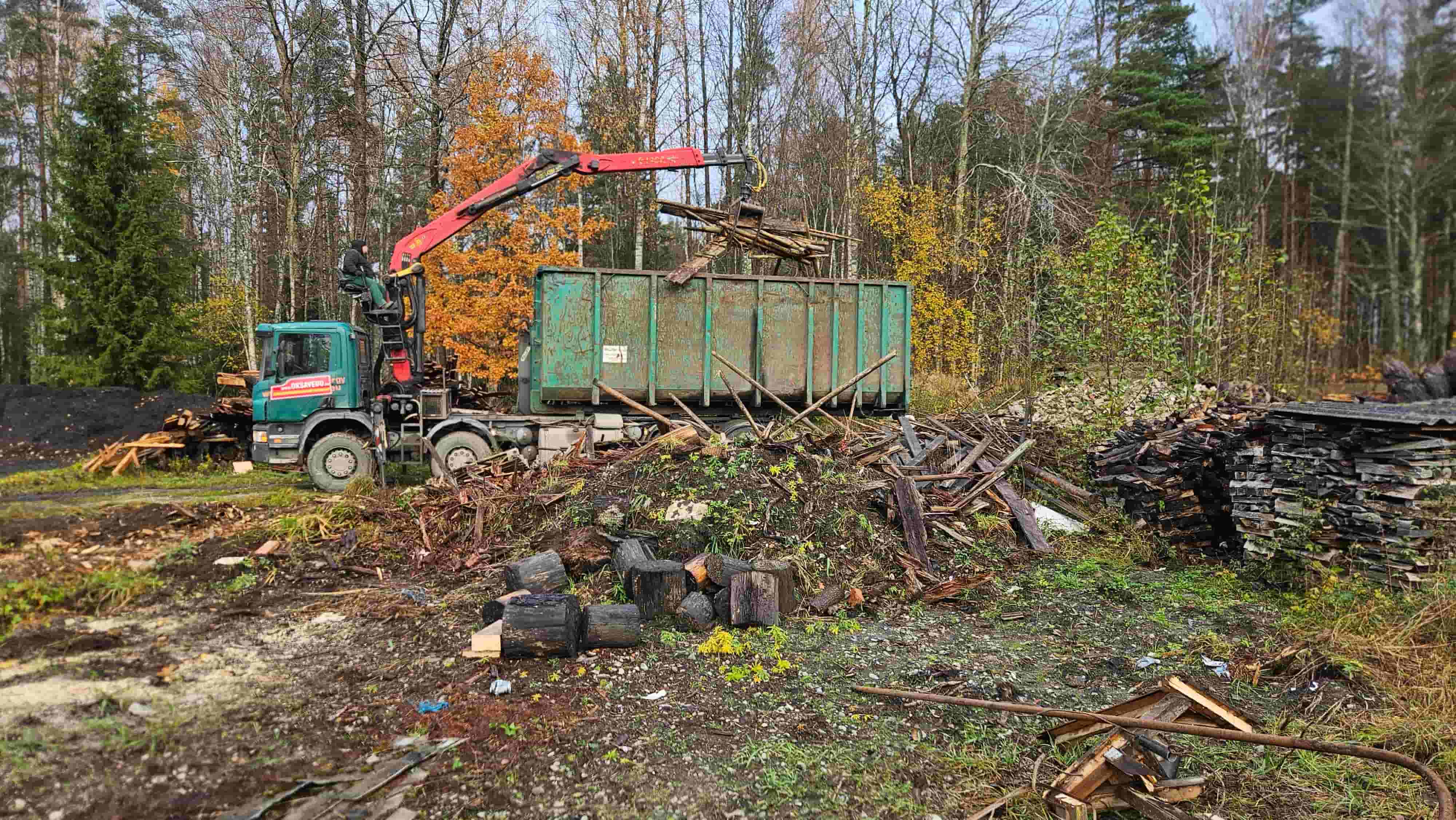 Kraanaauto laadib vanu lammutuslaudu konteinerisse.